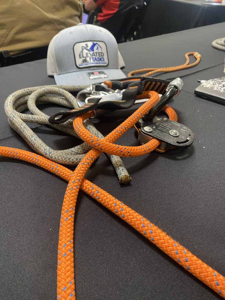 A Elevated Tasks branded hat sitting on a table with an assortment of tied knots and pulleys. 